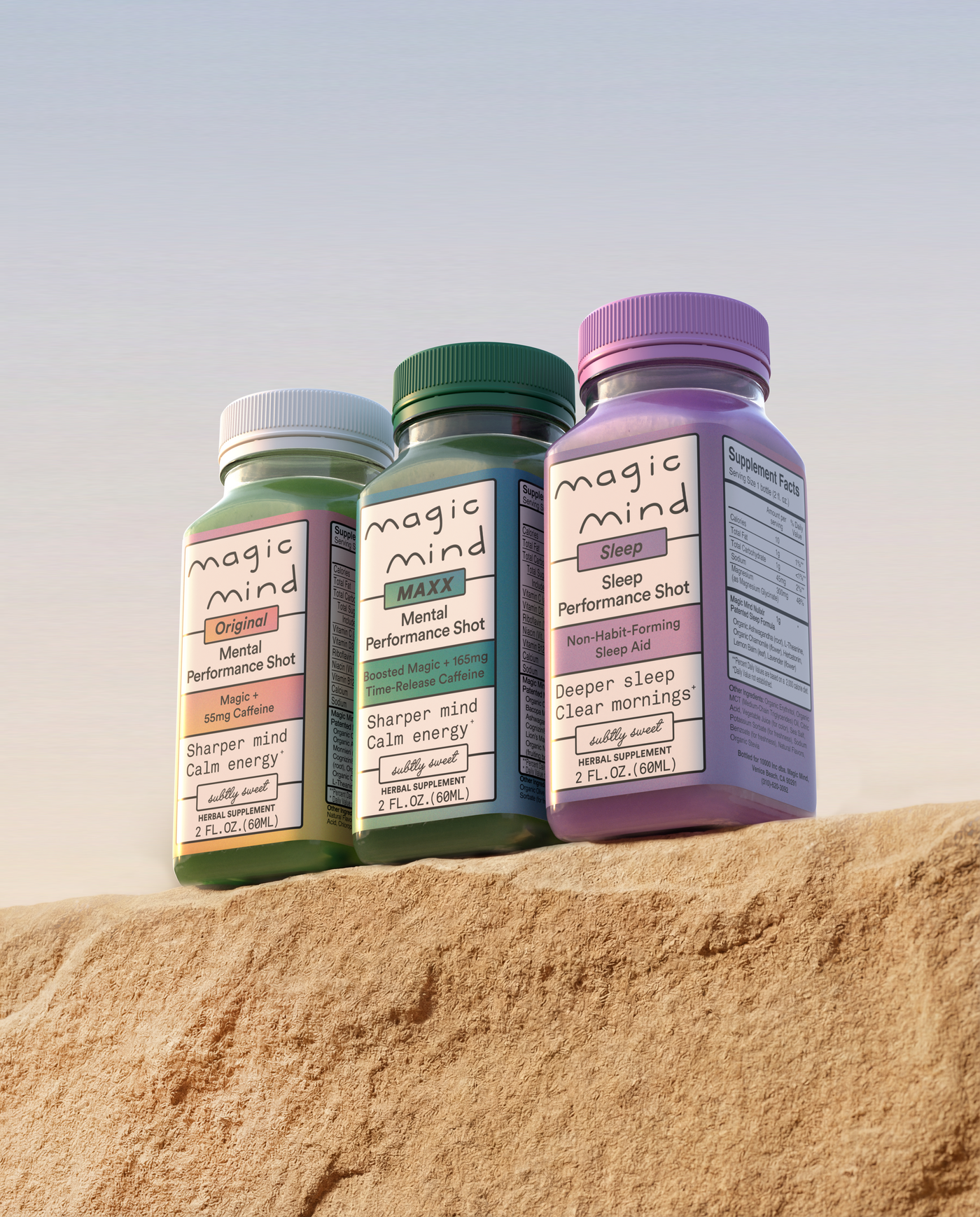 Three Magic Mind bottles; Original Mental Performance Shot, MAXX Mental Performance Shot, and Sleep Performance Shot, displayed on a rocky surface against a clear sky