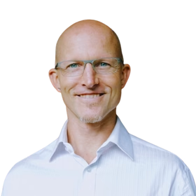 Dr. Dan Engle, MD, smiling headshot of a bald man wearing glasses and a white button-up shirt, on a transparent background