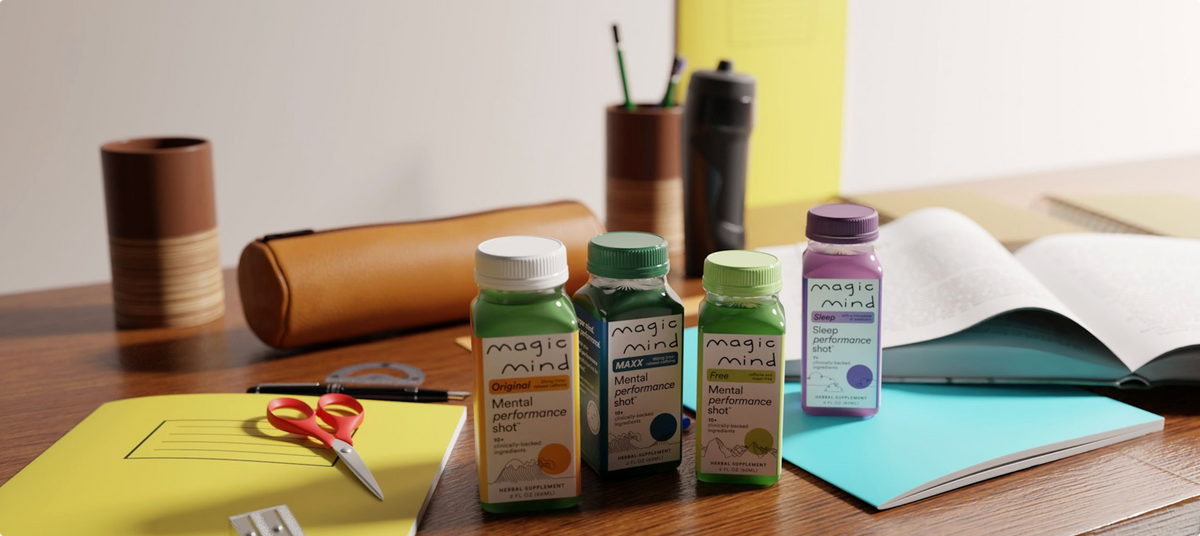 Four Magic Mind shot bottles on a desk with notebooks and study supplies.